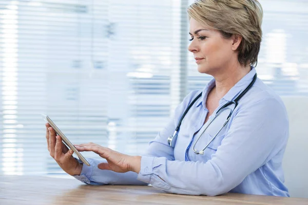 Médico sentado na mesa e usando tablet — Fotografia de Stock