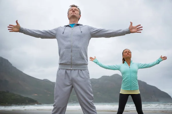 Couple debout avec les bras tendus sur la plage — Photo