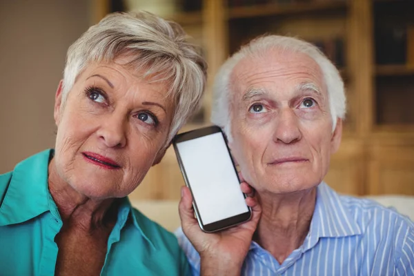 Coppia anziana che utilizza il telefono in soggiorno — Foto Stock