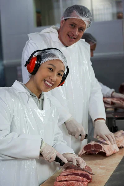 Butchers cutting meat at meat factory