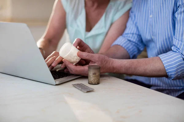 Senior para sprawdzanie leku na laptopie — Zdjęcie stockowe
