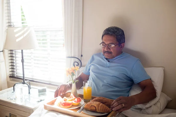 Senior man having breakfast on bed — Stock Photo, Image