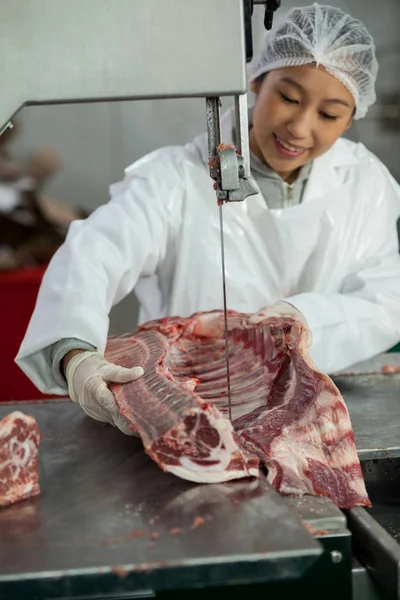 Carniceiro fêmea cortando carne crua — Fotografia de Stock