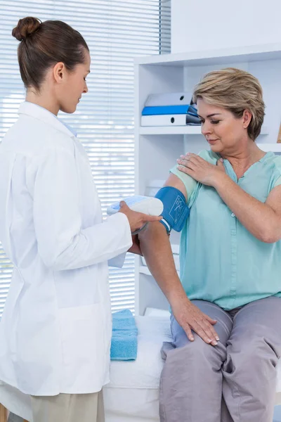 Medico che controlla la pressione sanguigna di un paziente — Foto Stock