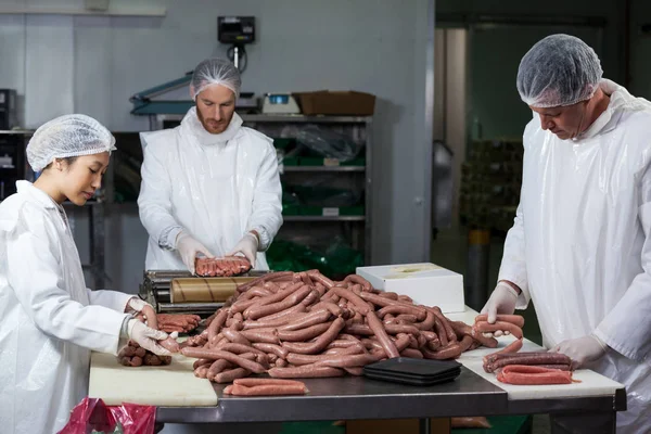 Butchers processing sausages — Stock Photo, Image