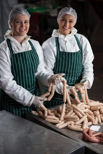 Carniceiros fêmeas processando salsichas — Fotografia de Stock