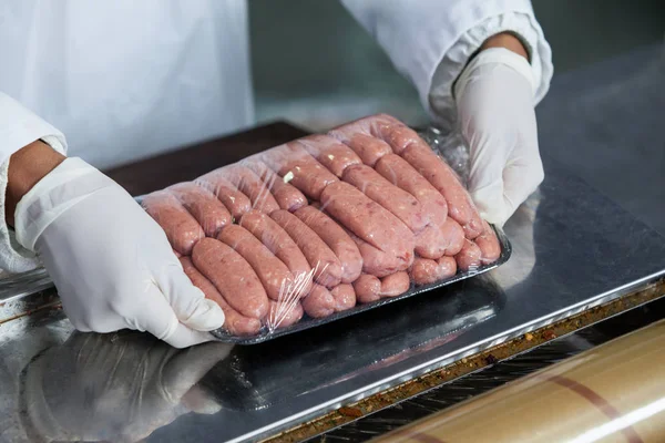 Açougueiro embalagem salsichas cruas — Fotografia de Stock