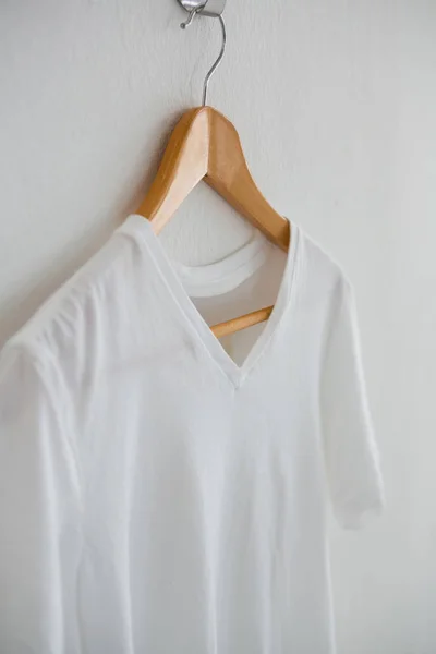 Белая футболка висит на вешалке — стоковое фото