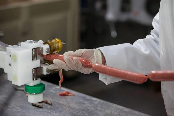 Female butcher processing sausages — Stock Photo, Image