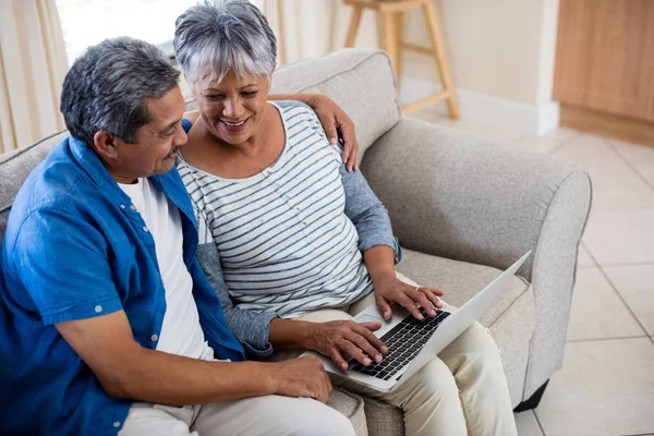 Casal sênior usando laptop na sala de estar — Fotografia de Stock