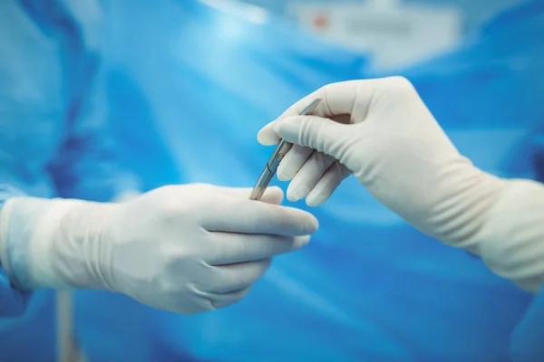 Un chirurgien passe le scalpel à un collègue — Photo
