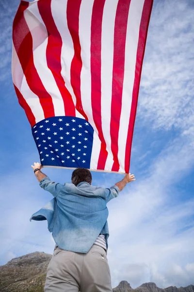 Amerikan bayrağı sahilde tutan adam — Stok fotoğraf