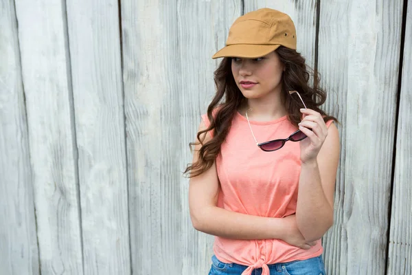 Woman in brown cap holding sunglasses — Stock Photo, Image