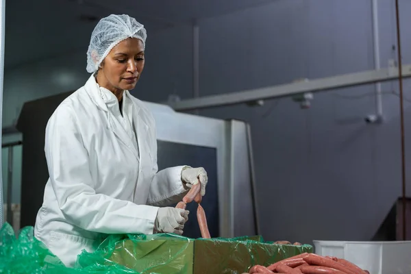 Salsichas de processamento de açougueiro feminino — Fotografia de Stock