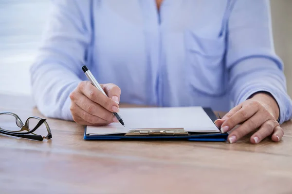 Mid section of doctor writing on clipboard — Stock Photo, Image