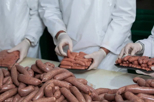 Butchers packing raw sausages — Stock Photo, Image