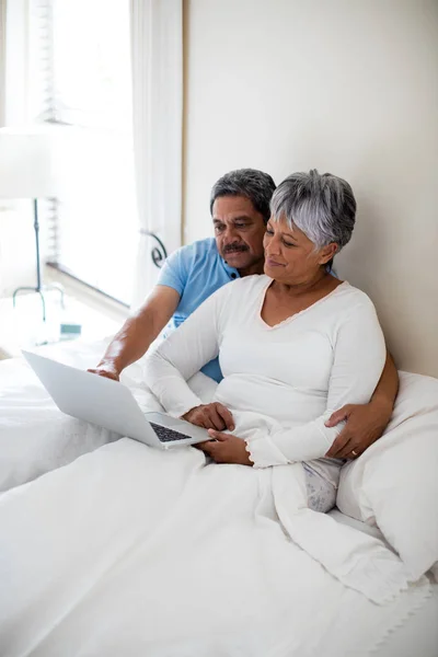 Coppia anziana utilizzando il computer portatile in camera da letto — Foto Stock