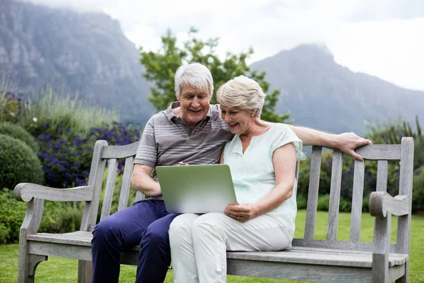 Seniorenpaar auf Bank und mit Laptop — Stockfoto