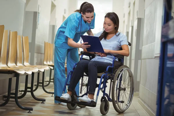 Krankenschwester hilft Patientin über Klemmbrett — Stockfoto