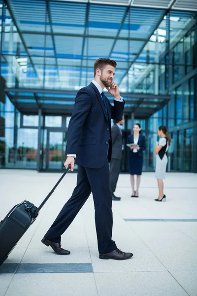 Бизнесмен с чемоданом разговаривает по телефону — стоковое фото