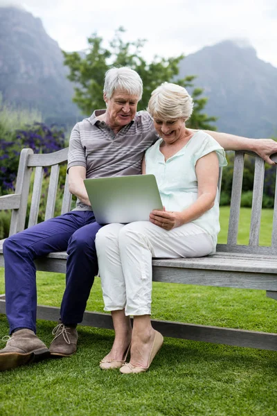 Couple sitting on bench and using laptop — Stock Photo, Image