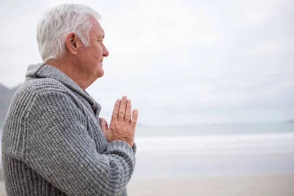 Starszy człowiek, zacierając ręce na plaży — Zdjęcie stockowe