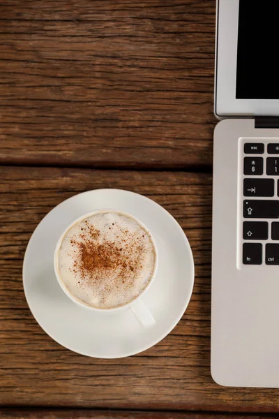 Laptop en kopje koffie op houten tafel — Stockfoto