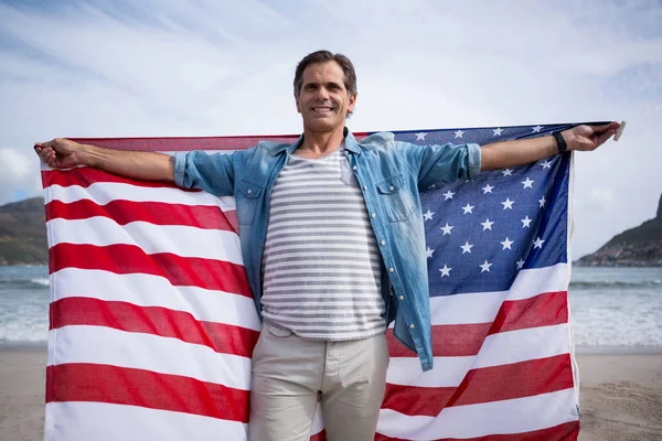 Uomo con bandiera americana sulla spiaggia — Foto Stock