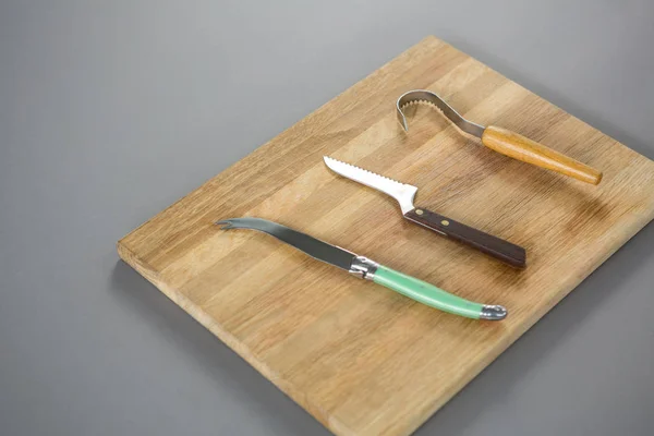 Herramientas de corte de queso sobre tabla de madera — Foto de Stock