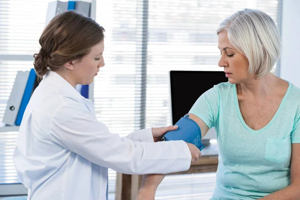 Medico donna che controlla la pressione sanguigna di un paziente — Foto Stock