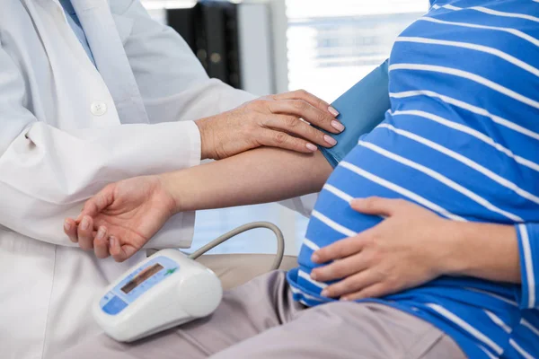 Médico feminino verificando a pressão arterial de um paciente — Fotografia de Stock