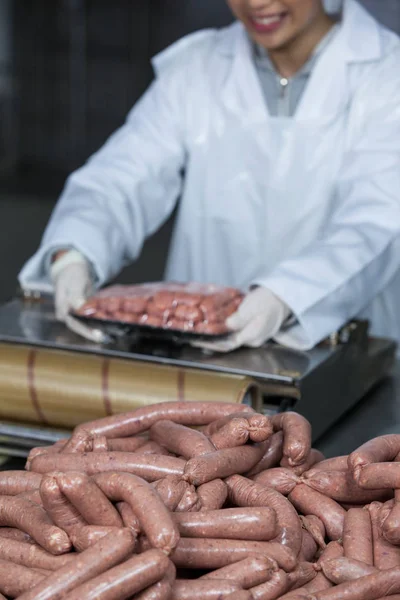 Açougueiro embalagem salsichas cruas — Fotografia de Stock