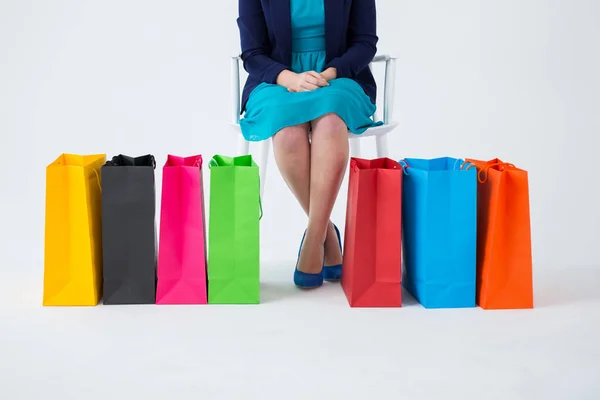 Renkli alışveriş torbaları ile oturan kadın — Stok fotoğraf