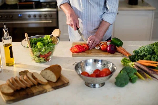 Senior man snijden groenten voor salade — Stockfoto