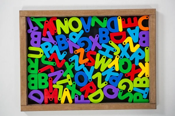 Alfabetos Jumbled multicoloridos na placa da ardósia — Fotografia de Stock