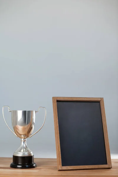 Troféu e quadro em mesa de madeira — Fotografia de Stock