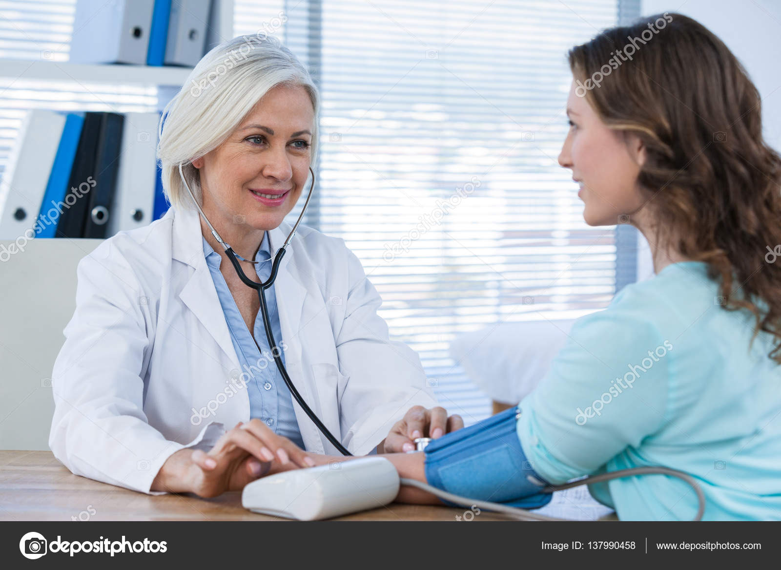 Female doctor checking blood pressure of patient Stock Photo by  ©Wavebreakmedia 137990458
