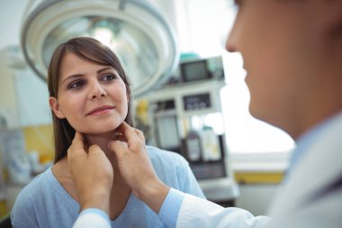 Doctor examining a female patients neck clipart