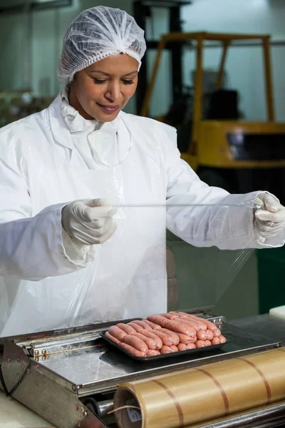 Açougueiro embalagem salsichas cruas — Fotografia de Stock