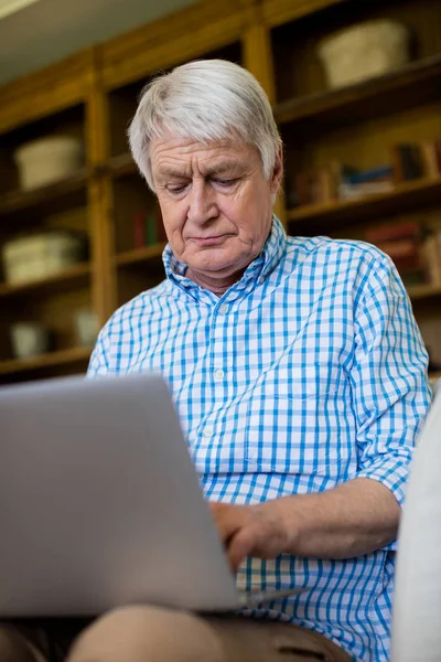 Uomo anziano utilizzando il computer portatile in soggiorno — Foto Stock