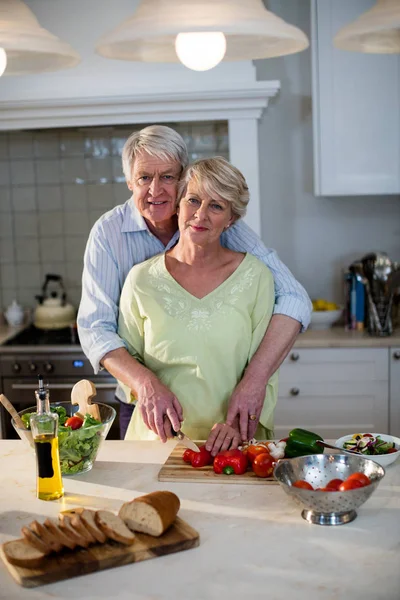 Pareja mayor cortando verduras en la cocina —  Fotos de Stock