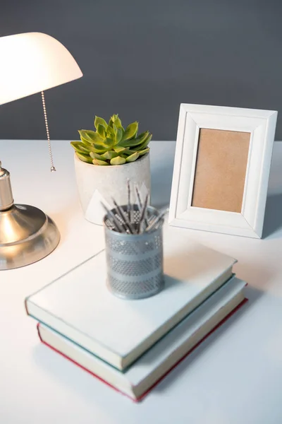 Masa lambası, resim çerçevesi ve kitaplar — Stok fotoğraf