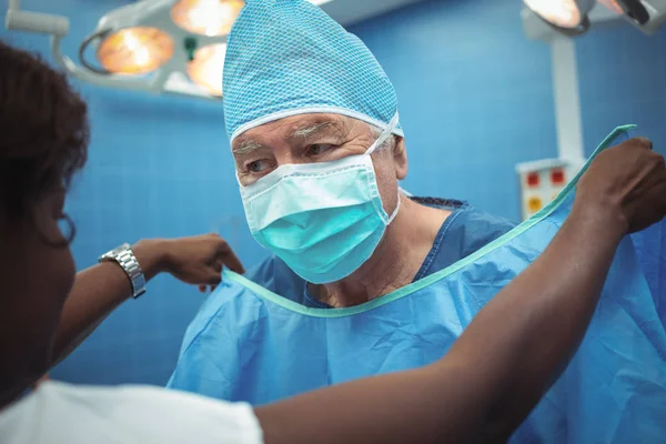 Хирург помогает своей коллеге носить халаты — стоковое фото