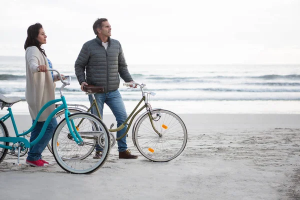 Par stående med cykel på stranden — Stockfoto