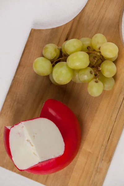 Queijo vermelho e uvas em tábua de madeira — Fotografia de Stock