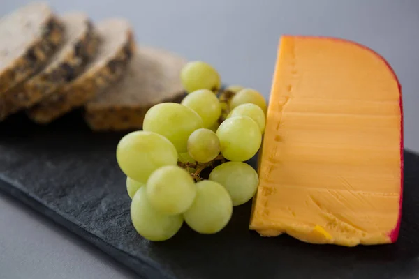 Gouda cheese and grapes on slate plate — Stock Photo, Image