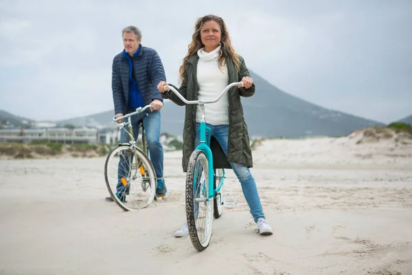 Pareja de pie con bicicleta en la playa —  Fotos de Stock