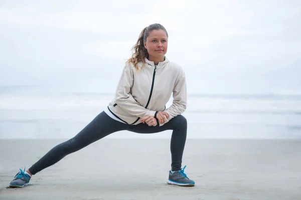 Kobieta, wykonywaniu ćwiczenia rozciągające na plaży — Zdjęcie stockowe
