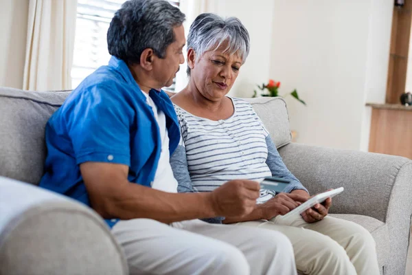 Senior paar met behulp van digitale tablet zittend — Stockfoto