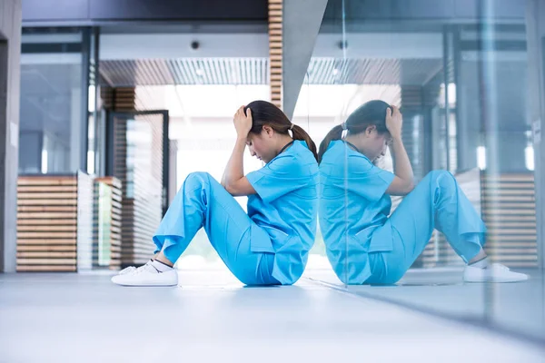 Gestresste Krankenschwester sitzt auf dem Boden — Stockfoto